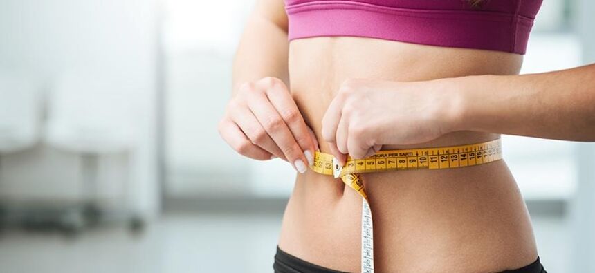 The girl measures the waistline